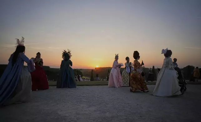 Costumed guests arrive in the gardens of the Versailles castle before the Great Masked Ball, in Versailles, outside Paris, Saturday, June 21, 2025. (AP Photo/Christophe Ena)