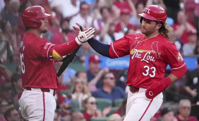 St. Louis Cardinals' Brendan Donovan (33) is congratulated by teammate Nolan Gorman after scoring during the third inning of a baseball game against the Cincinnati Reds Friday, June 20, 2025, in St. Louis. (AP Photo/Jeff Roberson)