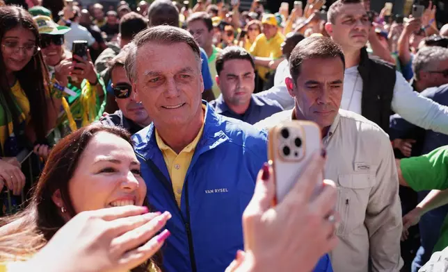 Former President Jair Bolsonaro poses for a selfie with a supporter upon arriving at a protest against his Supreme Court trial, in which he is accused of involvement in a 2022 coup attempt, in Sao Paulo, Sunday, June, 29, 2025. (AP Photo/Ettore Chiereguini)