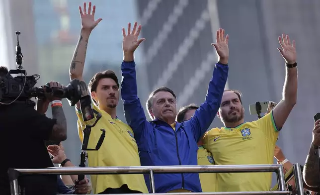 Former President Jair Bolsonaro, center, gestures to the crowd with his sons Jair Renan Bolsonaro, left, and Carlos Bolsonaro, during a protest against his Supreme Court trial, in which he is accused of involvement in a 2022 coup attempt, in Sao Paulo, Sunday, June, 29, 2025. (AP Photo/Ettore Chiereguini)