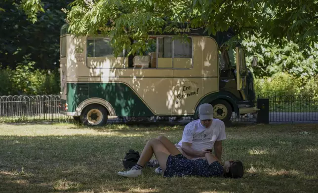 People lay on the grass in St James's Park, near an ice cream van, in London, Monday, June 30, 2025. (AP Photo/Alberto Pezzali)