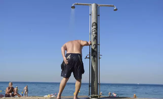 A man takes a shower at Alimos beach near Athens, Thursday, June 26, 2025, as the summer's first heat wave hits Greece, with temperatures expected to edge over 40 degrees Celsius, (104 Farenheit). (AP Photo/Petros Giannakouris)