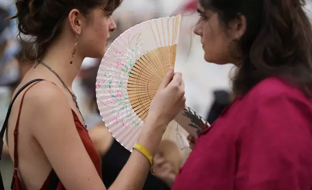 Demonstrators use fans to help with the high temperature during a protest against the housing crisis affecting Portugal, in Lisbon, Saturday, June 28, 2025. (AP Photo/Armando Franca)