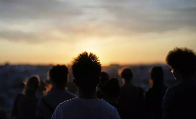 People watch the sun set from the Our Lady of the Hill viewpoint overlooking Lisbon at the end of a hot day in Lisbon, Friday, June 27, 2025. (AP Photo/Armando Franca)