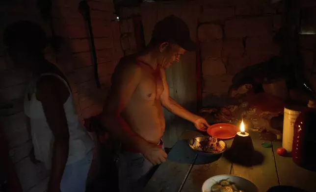 Edinector Vazquez prepares to eat dinner at his home lit by a gas lamp during a blackout in Minas, Havana province, Cuba, Monday, May 26, 2025. (AP Photo/Ramon Espinosa)