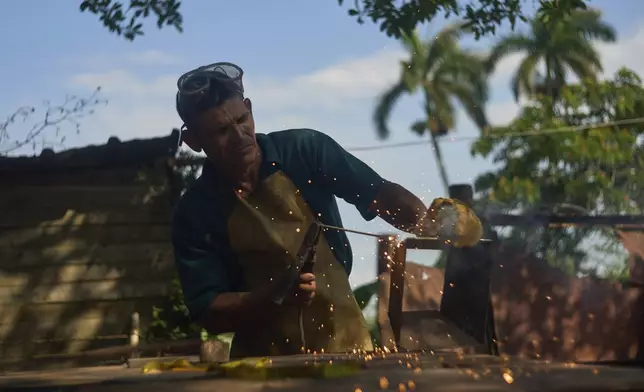 Blacksmith Edinector Vazquez builds a charcoal cooking stove to sell to residents looking to cook during blackouts in Minas, Havana province, Cuba, Friday, May 23, 2025. (AP Photo/Ramon Espinosa)