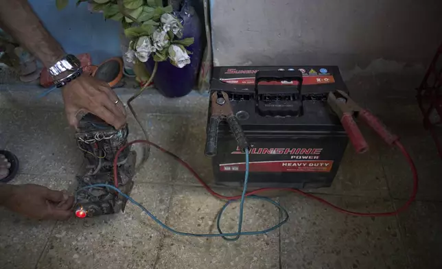 Angel Rodriguez uses a transformer from an old television to charge a battery in preparation for blackouts at his home in the Bahia neighborhood of Havana, Cuba, Monday, May 26, 2025. (AP Photo/Ramon Espinosa)