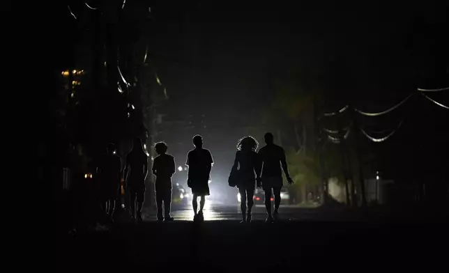 People walk in the dark during a blackout in Havana, Cuba, Wednesday, May 28, 2025. (AP Photo/Ramon Espinosa)