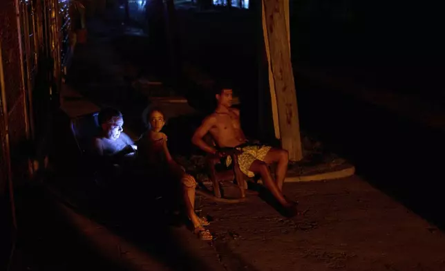 People sit in the cool evening air outside their homes during a blackout in Havana, Cuba, Wednesday, May 28, 2025. (AP Photo/Ramon Espinosa)
