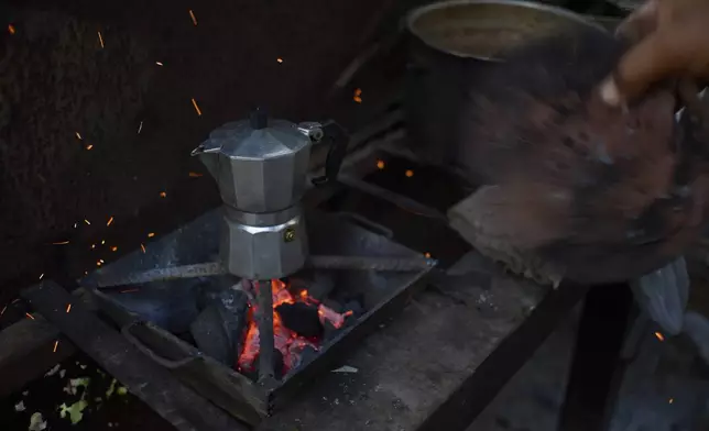 Edinector Vazquez stokes a coal fire as he makes coffee during a blackout in Minas, Havana province, Cuba, Monday, May 26, 2025. (AP Photo/Ramon Espinosa)