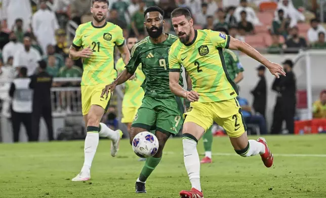 Saudi Arabia's Feras Albrikan, center, is challenged by Australia's Milos Degenek, right, during the World Cup 2026 Group C qualifying soccer match between Saudi Arabia and Australia at King Abdullah Stadium in Jeddah, Saudi Arabia, Tuesday, June 10, 2025. (AP Photo)