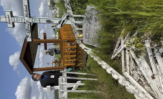 Deacon Michael Lucius of Toronto visits the gravesite of Matushka Olga Michael in Kwethluk, Alaska, on June 18, 2025, a day before she became the first female Orthodox saint in North America. In the foreground is the grave of Olga's husband, Nicolai Michael, who was a priest in Kwethluk. (AP Photo/Mark Thiessen)