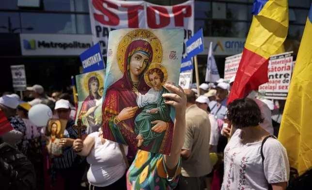 A woman holds a religious icon during a rally by right wing groups and their supporters opposing same sex marriage and sexual education in schools, ahead of the Bucharest Pride parade in Bucharest, Romania, Saturday, June 7, 2025. (AP Photo/Andreea Alexandru)