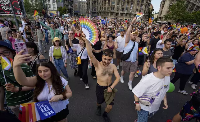 People dance while holding rainbow flags during the Bucharest Pride Parade, in Bucharest, Romania, Saturday, June 7, 2025. (AP Photo/Andreea Alexandru)