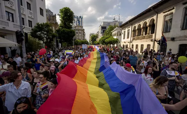People hold a rainbow flag banner during the gay pride parade in Bucharest, Romania, Saturday, June 7, 2025. (AP Photo/Andreea Alexandru)