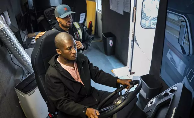 Trucking student Mohammed Kamal, left, overseen by instructor Tom Panton, practices driving a tractor-trailer truck in a simulation at the Driving Academy on Tuesday, June 10, 2025 in Linden, N.J. (AP Photo/Angelina Katsanis)