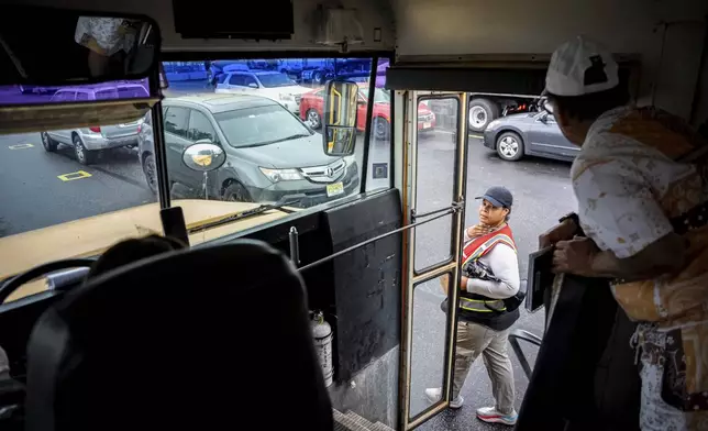 An instructor checks in on students practicing in a school bus at the Driving Academy on Tuesday, June 10, 2025 in Linden, N.J., where students prepare to obtain a Commercial Driver’s License (CDL) with multilingual instructors. (AP Photo/Angelina Katsanis)