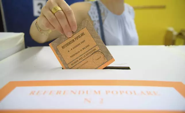 A woman casts her ballot in a box for referendums on citizenship and job protections, at a polling station in Milan, Italy, Sunday, June 8, 2025. (Claudio Furlan/LaPresse via AP)