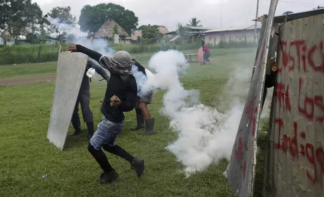 An anti-government protester hurls back a tear gas canister during clashes with police at the Indigenous Embera community of Arimae, Panama, Thursday, June 5, 2025. (AP Photo/Matias Delacroix)