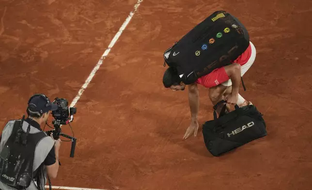 Serbia's Novak Djokovic touches the groung as he leaves the semifinal match of the French Tennis Open against Italy's Jannik Sinner at the Roland-Garros stadium in Paris, Friday, June 6, 2025. (AP Photo/Christophe Ena)