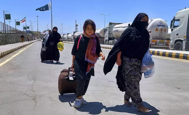 Pakistani families, who were stuck in Iran due to Israeli strikes on Iran, walk toward immigration counter after entering in homeland through Taftan, a joint border crossing point on Pakistan Iran border, Wednesday, June 18, 2025. (AP Photo/Fateh Muhammad)