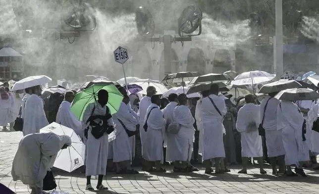 Cooling fans spray water over Muslim pilgrims gathered atop the rocky hill known as the Mountain of Mercy, on the Plain of Arafat, during the annual Hajj pilgrimage near the holy city of Mecca, Saudi Arabia, Thursday, June 5, 2025. (AP Photo/Amr Nabil)