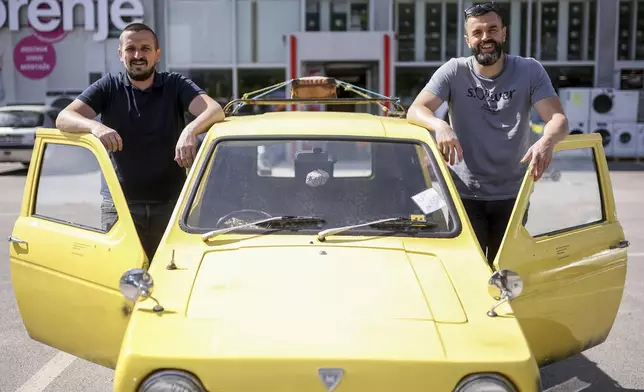 Tarik Fatic, left, and his brother Mirnes pose for a photo next to the Reliant Regal, an exact copy of the famous BBC TV show "Only Fools and Horses" iconic yellow car in Hadzici, suburb of Sarajevo, Bosnia, Wednesday, June 4, 2025. (AP Photo/Armin Durgut)