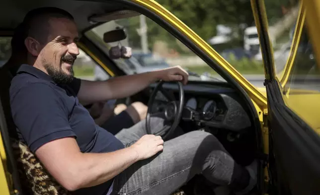 Tarik Fatic sits down in the Reliant Regal, an exact copy of the famous BBC TV show "Only Fools and Horses" iconic yellow car in Hadzici, suburb of Sarajevo, Bosnia, Wednesday, June 4, 2025. (AP Photo/Armin Durgut)