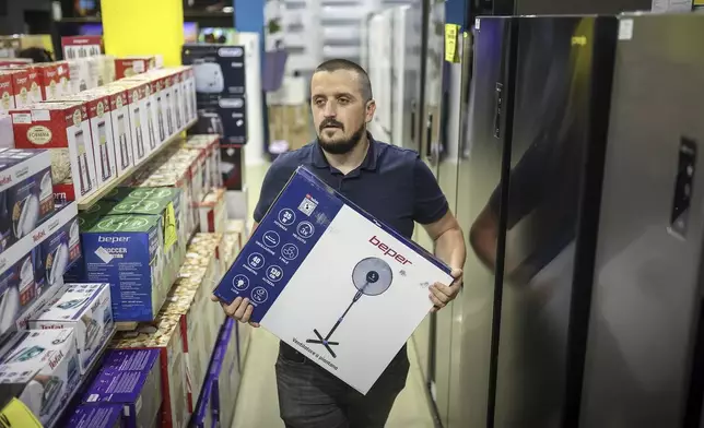 Tarik Fatic, one of the owners of "Only fools and horses ltd." home appliance store, brings a fan to a customer in Hadzici, suburb of Sarajevo, Bosnia, Wednesday, June 4, 2025. (AP Photo/Armin Durgut)