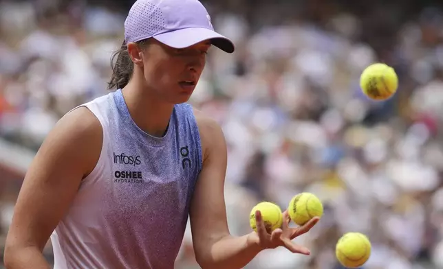 Poland's Iga Swiatek chooses the balls to serve against Kazakhstan's Elena Rybakina during their fourth round match of the French Tennis Open, at the Roland-Garros stadium, in Paris, Sunday, June 1 2025. (AP Photo/Christophe Ena)