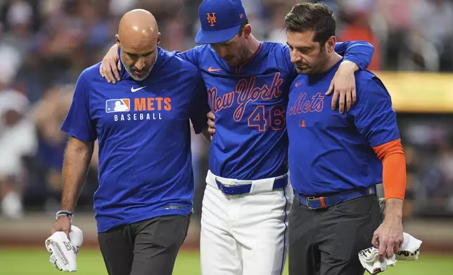 New York Mets pitcher Griffin Canning is helped off the field by head athletic trainer Joseph Golia, right, and assistant athletic trainer Bryan Baca during the third inning of a baseball game against the Atlanta Braves Thursday, June 26, 2025, in New York. (AP Photo/Frank Franklin II)
