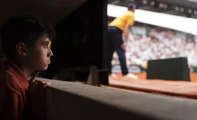 A ball boy follows the fourth round match of the French Tennis Open between China's Zheng Qinwen and Russia's Liudmila Samsonova, at the Roland-Garros stadium, in Paris, Sunday, June 1 2025. (AP Photo/Lindsey Wasson)