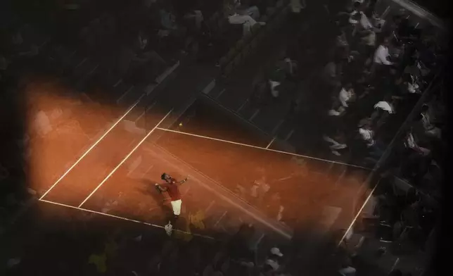Fans are reflected in glass from an upper tribune as France's Gael Monfils serves against Britain's Jack Draper during a second-round match of the French Tennis Open at the Roland-Garros stadium in Paris, Thursday, May 29, 2025. (AP Photo/Lindsey Wasson)