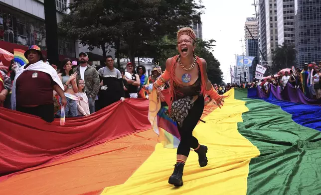 A reveler runs on a large rainbow flag during the annual Pride parade marking LGBTQ+ Pride Month, in Sao Paulo, Sunday, June 22, 2025. (AP Photo/Ettore Chiereguini)