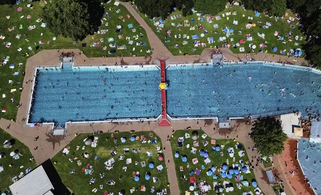 People fill a public pool in Frankfurt, Germany, on a warm Saturday, June 21, 2025. (AP Photo/Michael Probst)