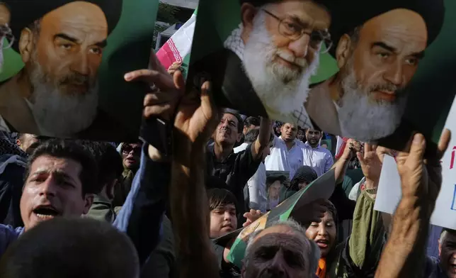 Iranian protesters hold up posters showing the Supreme Leader Ayatollah Ali Khamenei, center, and the late revolutionary founder Ayatollah Khomeini in a protest following the U.S. attacks on Iranian nuclear sites Sunday, June 22, 2025, in Tehran, Iran. (AP Photo/Vahid Salemi)