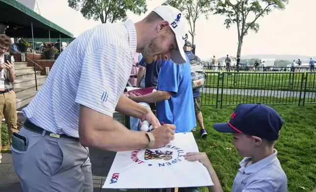 Matt Vogt, right, signs autographs for fans as he makes his way to the first tee for a practice round for the 2025 US Open golf championship at Oakmont Country Club in Oakmont, Pa. Monday, June 9, 2025. (AP Photo/Gene J. Puskar)