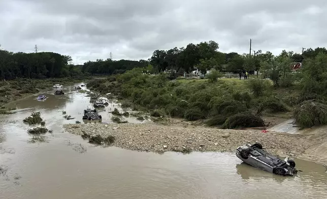 Vehicles sit in the river after being swept away by floodwaters in San Antonio, Tx., Thursday, June 12, 2025. (AP Photo/Lekan Oyekanmi)