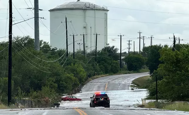 A police vehicle blocks a flooded roadway in San Antonio, Tx., where a vehicle was stranded after heavy rains in the city on Thursday, June 12, 2025. (AP Photo/Lekan Oyekanmi)