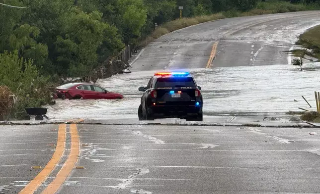 A police vehicle blocks a flooded roadway in San Antonio, Tx., where a vehicle was stranded after heavy rains in the city on Thursday, June 12, 2025. (AP Photo/Lekan Oyekanmi)