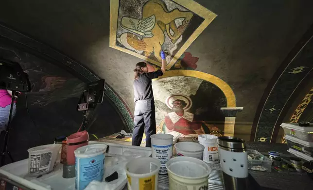 Standing on a 32-foot-tall scaffold, art conservationist Kate Pirelli works on cleaning a mural by Max Vanka depicting a lion and St. Mark inside St. Nicholas Croatian Catholic Church in Millvale, Pa., Monday, May 19, 2025. (AP Photo/Gene J. Puskar)