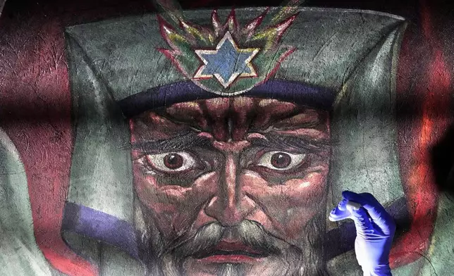 Art conservator Naomi Ruiz works on the face of Moses in a mural by Maxo Vanka inside St. Nicholas Croatian Catholic Church in Millvale, Pa., Wednesday, Feb. 19, 2025. (AP Photo/Gene J. Puskar)