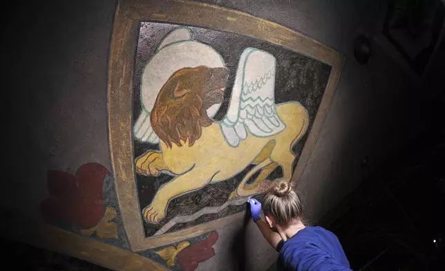 Art conservation technician Christina Cichra works on touching up a lion, symbol of the Gospel of St. Mark, in a mural by Maxo Vanka inside St. Nicholas Croatian Catholic Church in Millvale, Pa., Feb 13, 2025. (AP Photo/Gene J. Puskar)