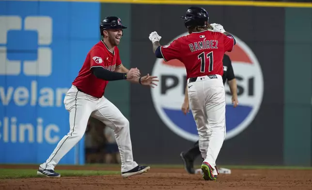 Cleveland Guardians' David Fry, left, congratulates Jose Ramirez (11) for his game winning single at the end of the 10th inning of a baseball game against the Toronto Blue Jays, Wednesday, June 25, 2025, in Cleveland. (AP Photo/Phil Long)