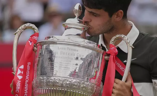 Carlos Alcaraz of Spain kisses the winners trophy as he poses for photographs after defeating Jiri Lehecka of the Czech Republic, in the men's singles final of the Queens Club tennis championships in London, Sunday, June 22, 2025. (AP Photo/Joanna Chan)