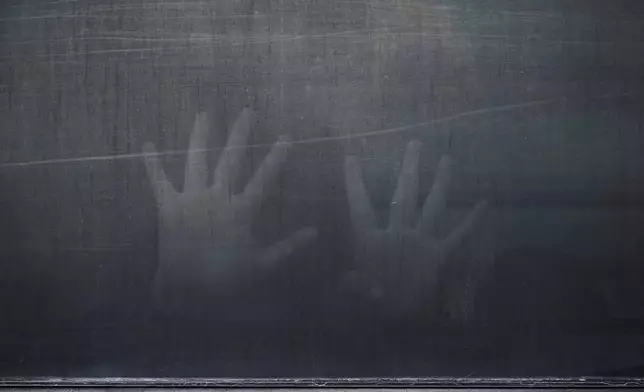 A woman from Peru signals through the barred and tinted windows of a bus after she was detained following an appearance at immigration court, Monday, June 23, 2025, in San Antonio. (AP Photo/Eric Gay)