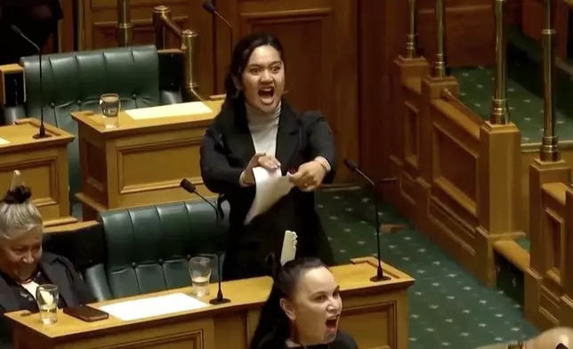 In this image from video provided by New Zealand Parliament TV, lawmaker Hana-Rāwhiti Maipi-Clarke tears papers as she performs a Māori haka to protest a proposed law during a session of Parliament in Wellington, New Zealand, on Nov. 14, 2024, (New Zealand Parliament TV via AP)
