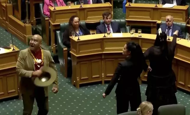 In this image from video provided by New Zealand Parliament TV, lawmakers, from foreground left, Rawiri Waititi, Hana-Rāwhiti Maipi-Clarke and Debbie Ngarewa-Packer perform a Māori haka to protest a proposed law during a session of Parliament in Wellington, New Zealand, on Nov. 14, 2024, (New Zealand Parliament TV via AP)