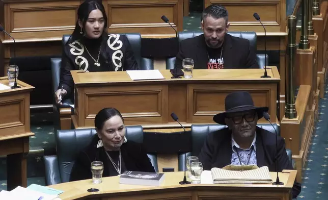 New Zealand lawmakers Hana-Rāwhiti Maipi-Clarke, top left, Debbie Ngarewa-Packer, bottom left, and Rawiri Waititi, bottom right, watch as other legislators debate their proposed bans in parliament in Wellington on Thursday, June 5, 2025. (AP Photo/Charlotte Graham-McLay)