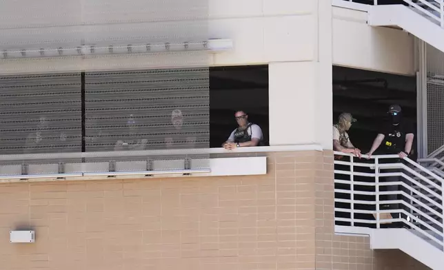 FILE - Federal law enforcement wait in a parking garage to take people into custody outside immigration court, May 21, 2025, in Phoenix. (AP Photo/Ross D. Franklin, File)